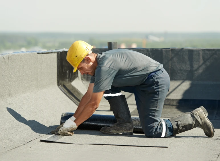 Man wearing a t-shirt, pants, a yellow hard hat, and black boots